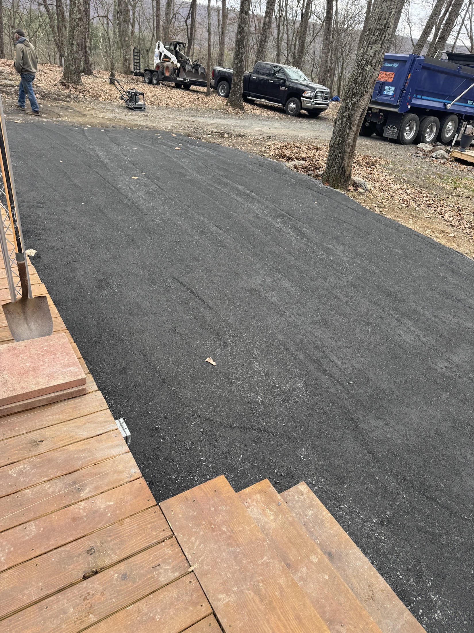 Fresh driveway surface work with trucks and equipment nearby