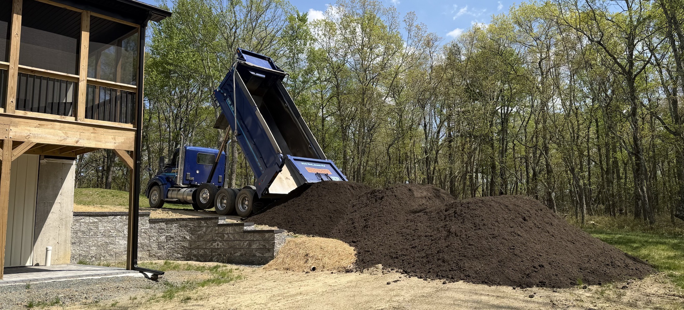 Dump truck delivering topsoil near a retaining wall