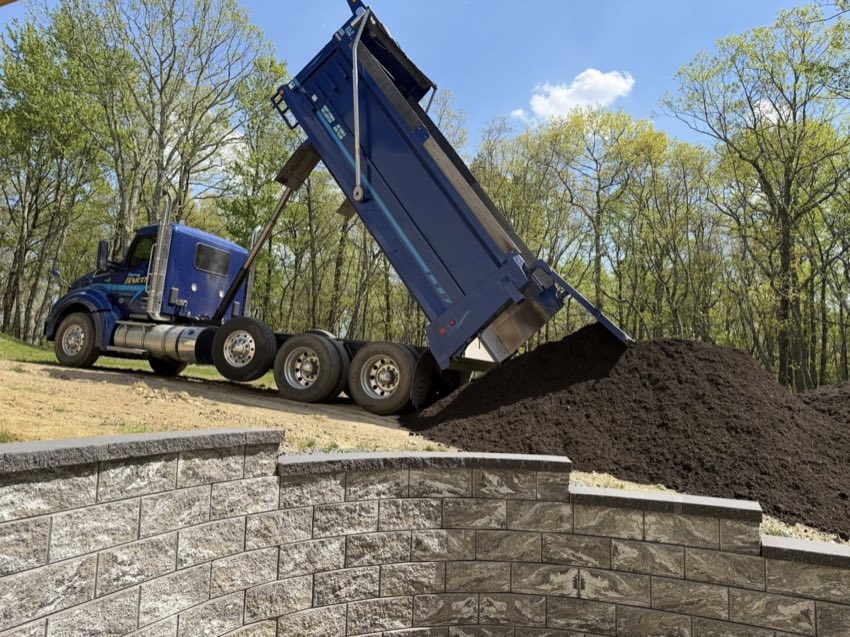 Topsoil delivery above block retaining wall